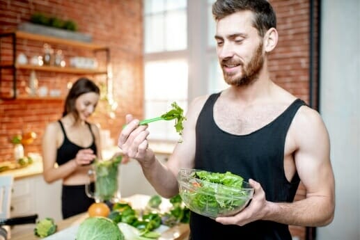 young-sports-couple-having-snack-with-healthy-salad-green-smoothie-kitchen-home